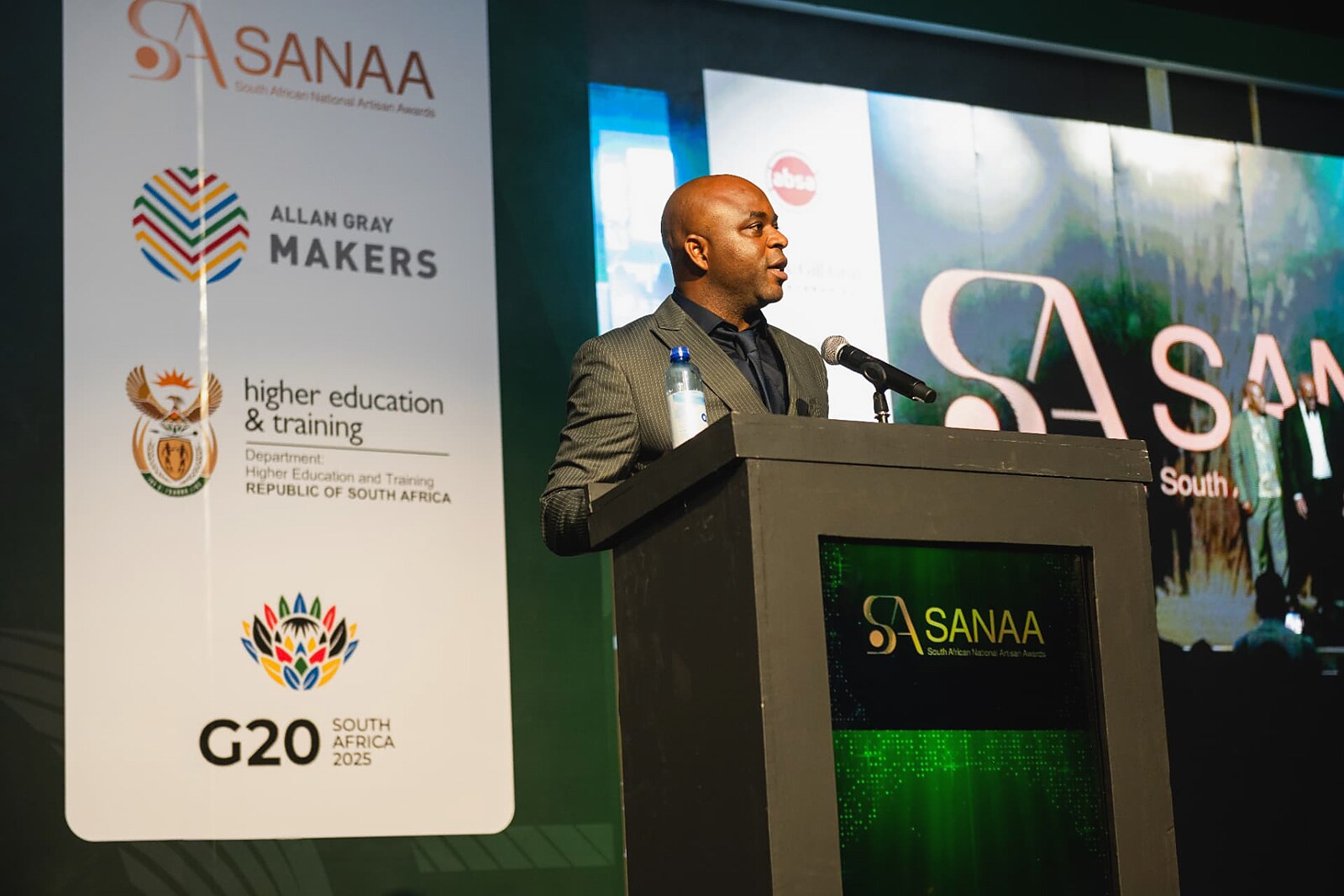 Speaker addressing the gala beside the sponsor banner wall