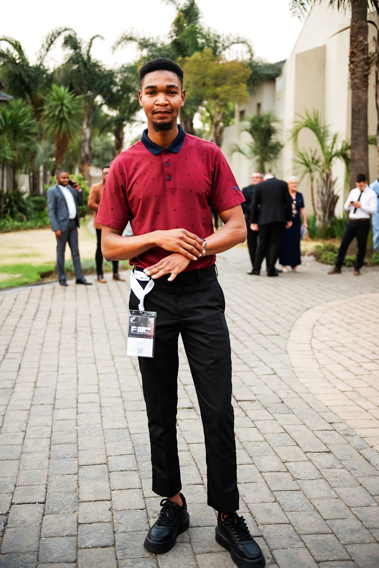 Young artisan with an event lanyard posing on the walkway outside the SANAA 2026 venue