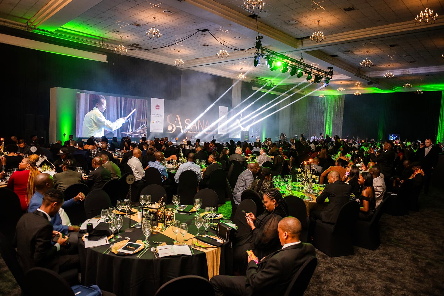 Wide view of the SANAA 2026 ballroom with green stage lighting and full tables