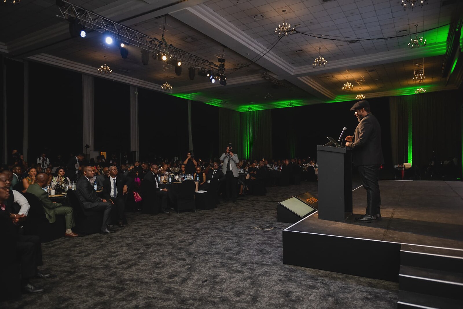 Wide view of the ballroom audience listening to the stage address