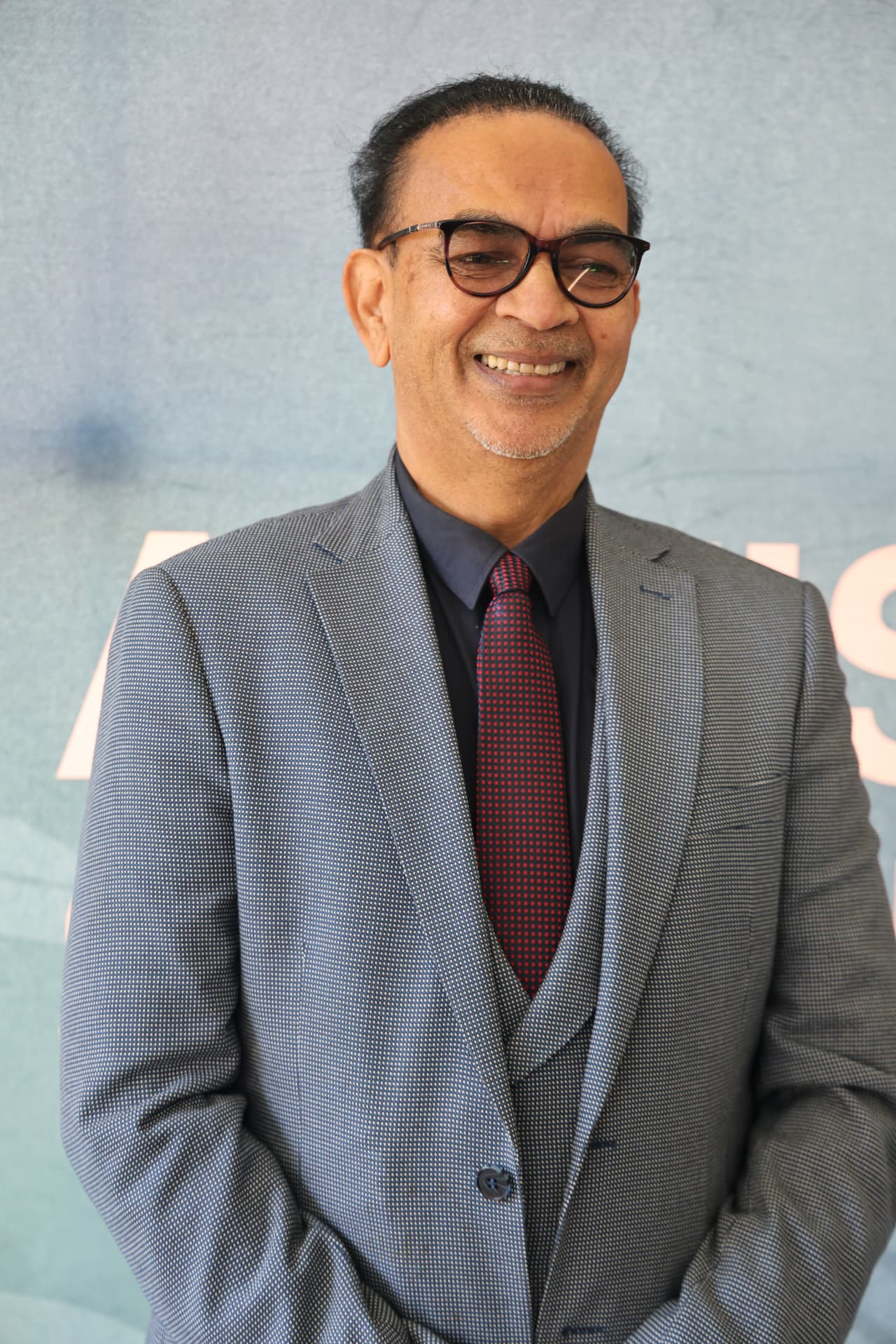 SANAA selection committee chairperson smiling in front of the awards backdrop