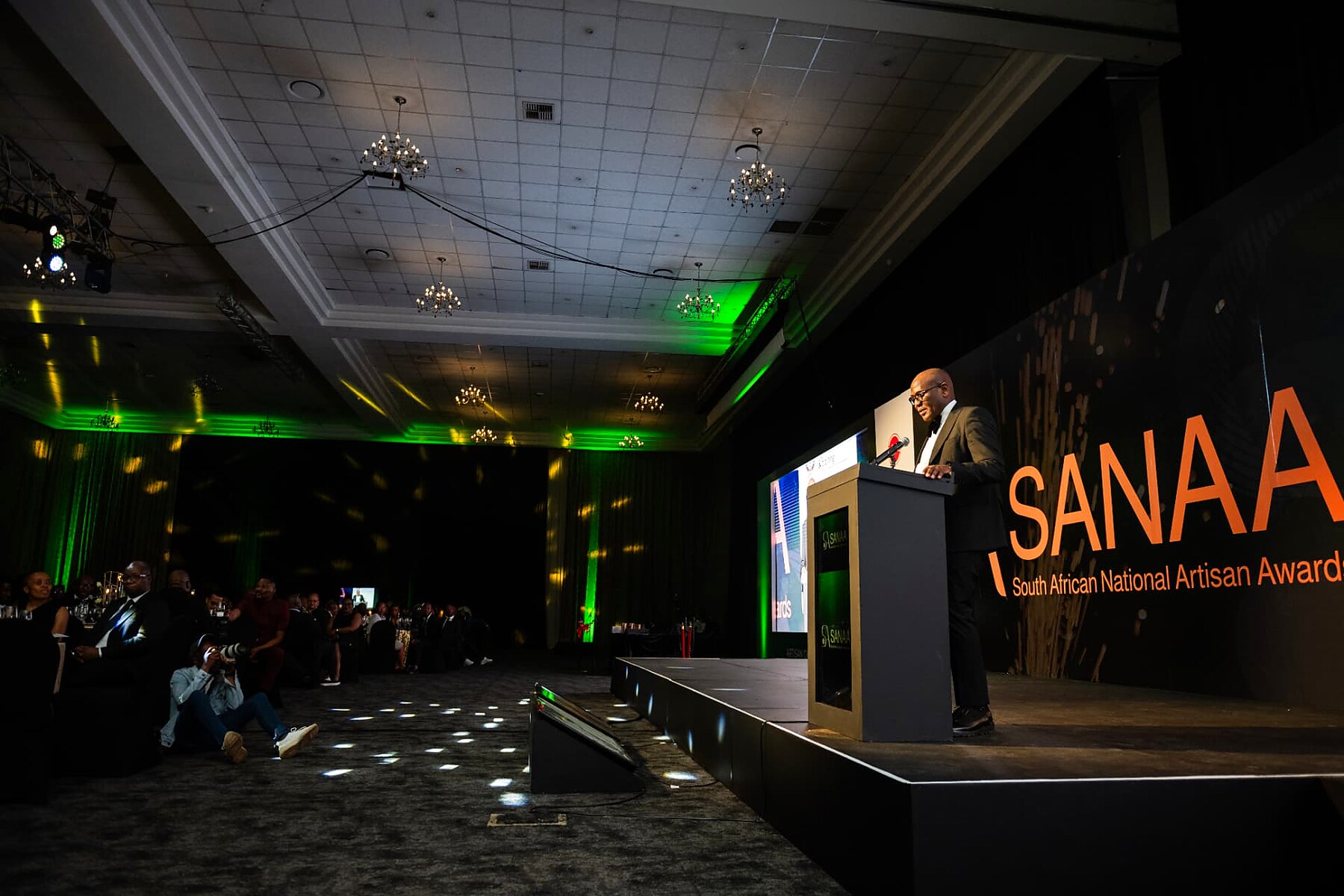 Wide view of the ballroom as a speaker addresses guests from the stage