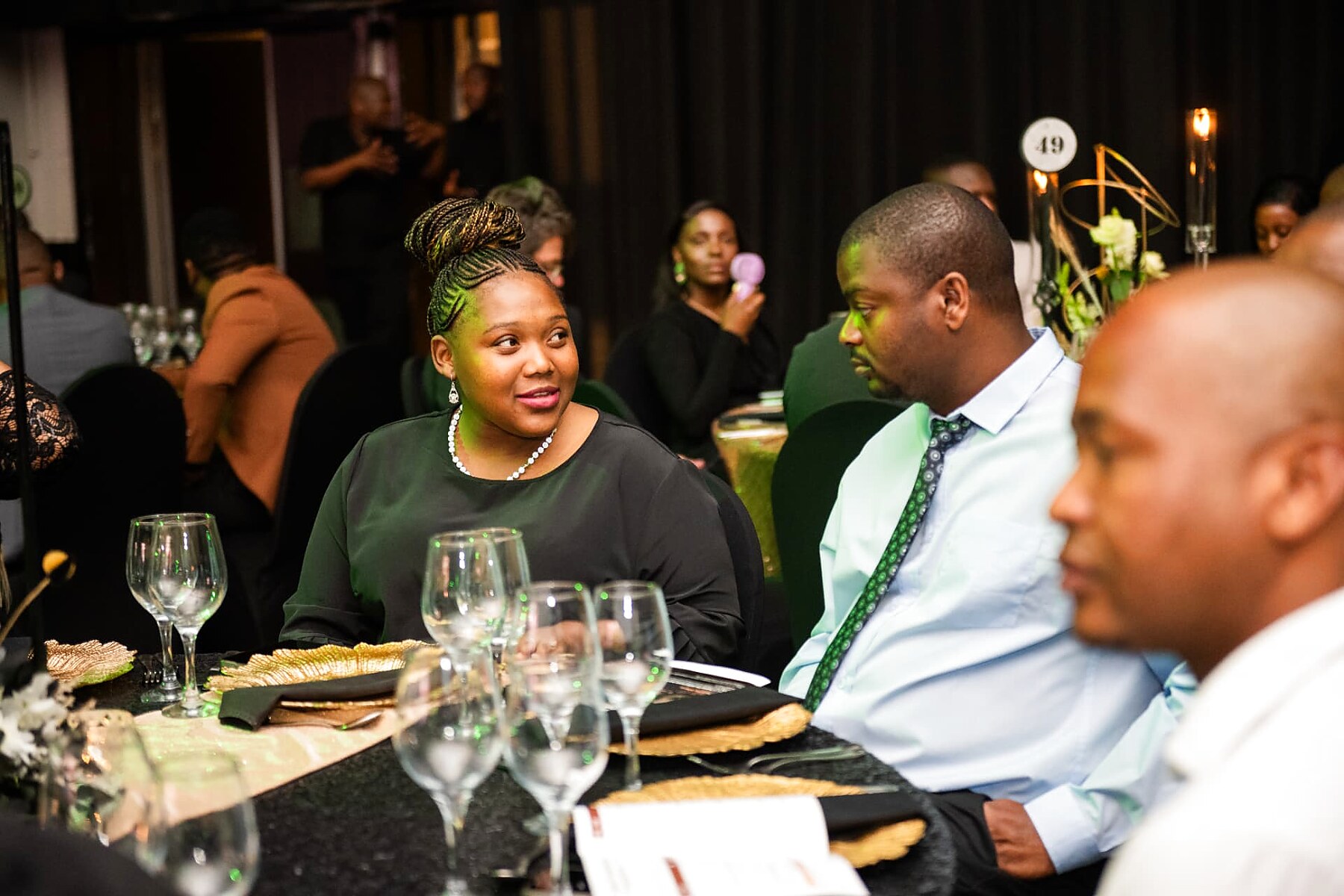 Guests seated together under green stage lighting at the gala