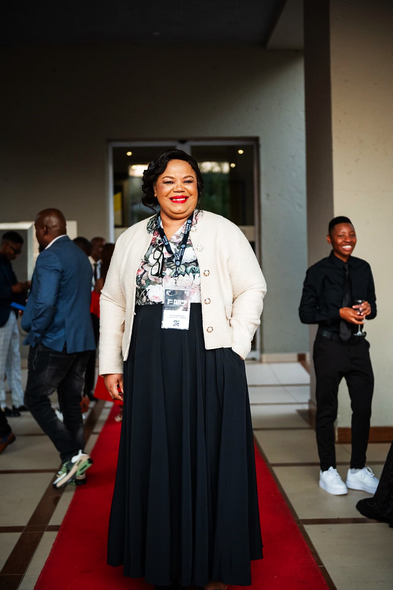 Guest in a cream jacket and long black skirt smiling on the SANAA 2026 red carpet