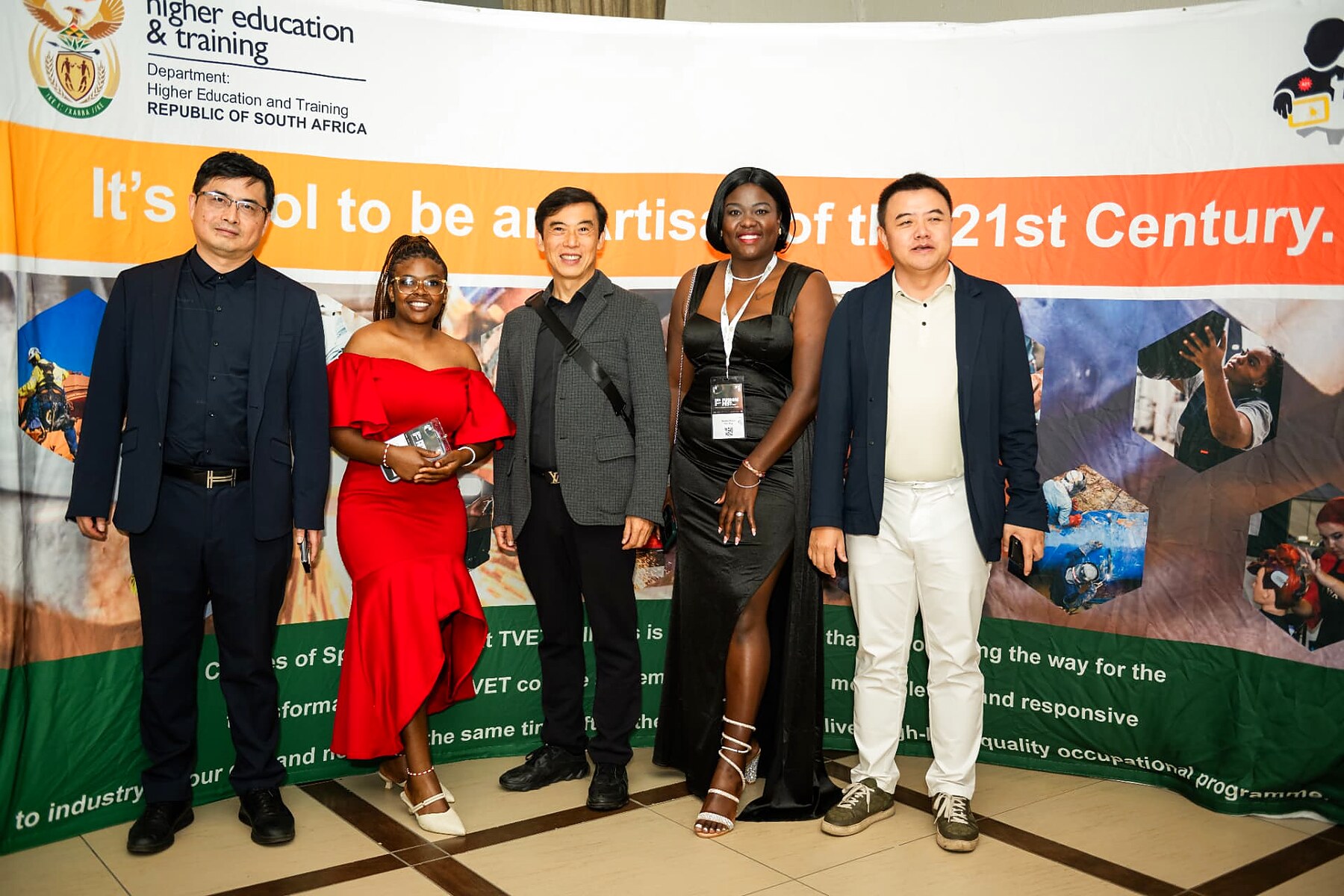 Group of five delegates posing in front of the Department of Higher Education and Training banner