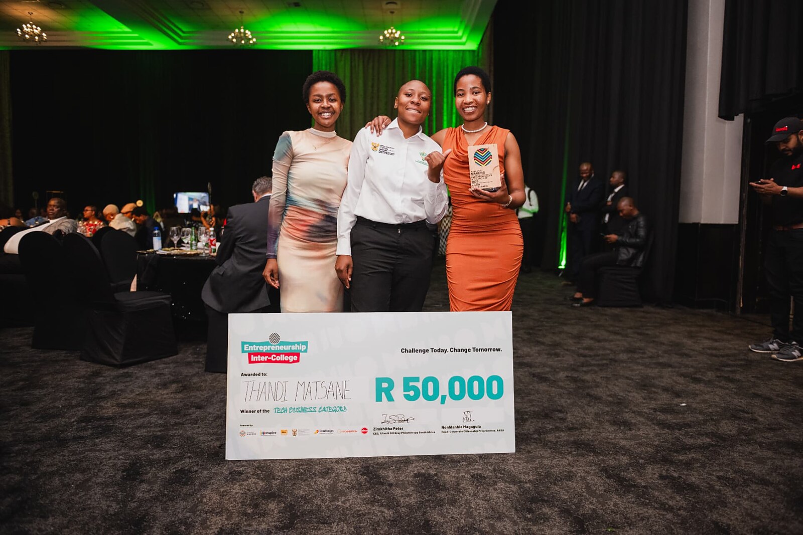 Three young women celebrating with the Entrepreneurship Inter-College R50,000 tech business category cheque