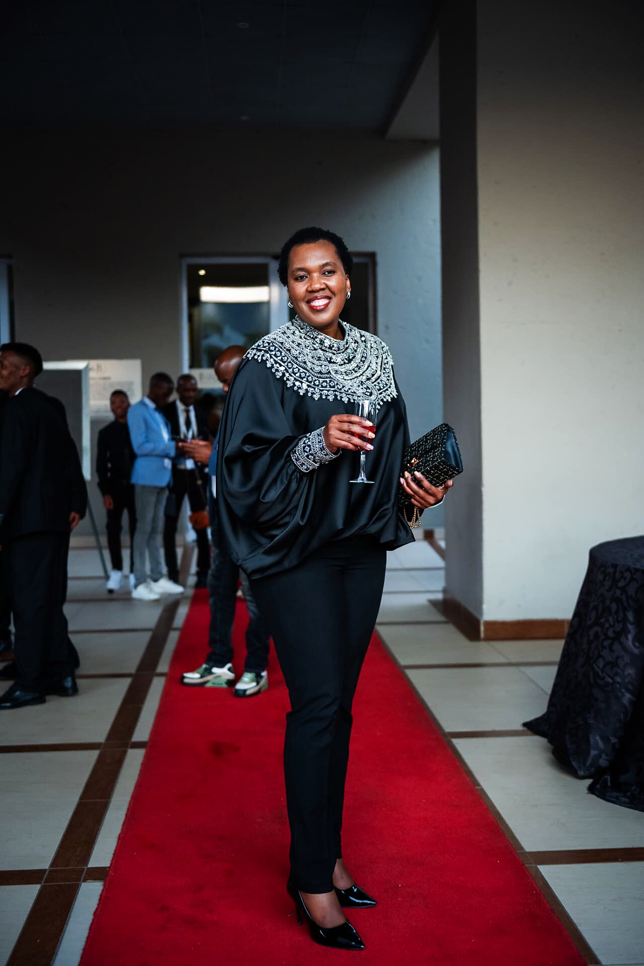 Guest in a beaded black outfit holding a glass on the SANAA 2026 red carpet