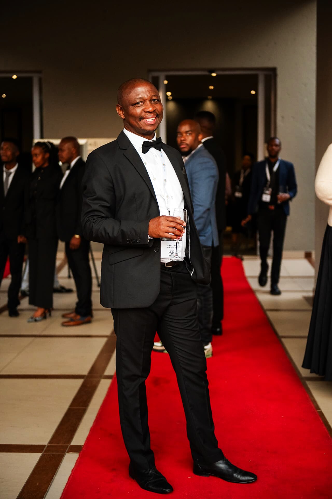 Guest in a bow tie smiling as he walks the SANAA 2026 red carpet