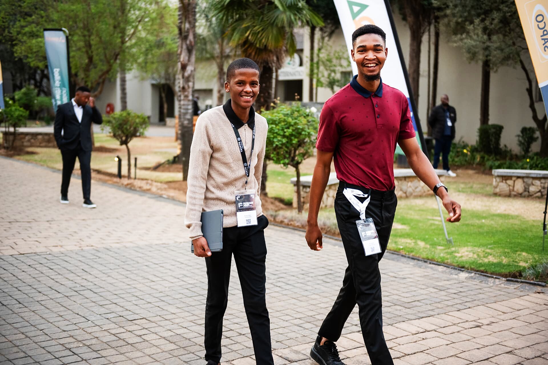 Two young artisans with event lanyards walking into the SANAA 2026 venue