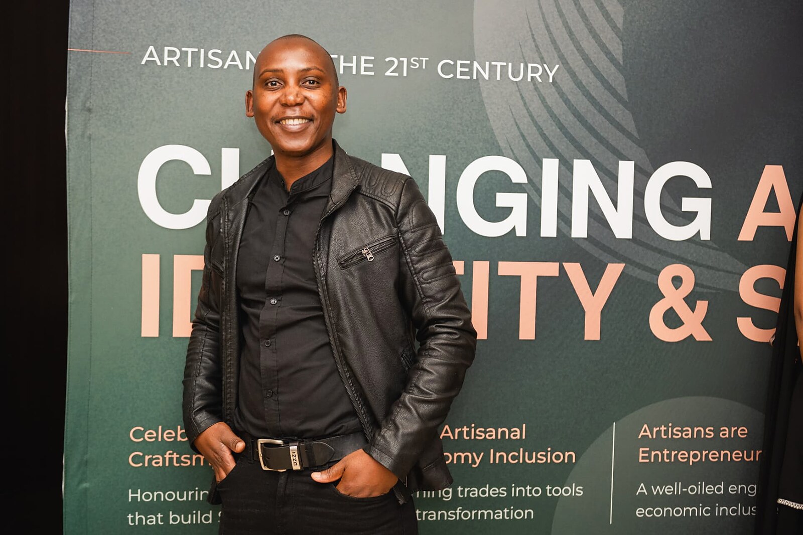Guest posing in front of the Artisans of the 21st Century banner
