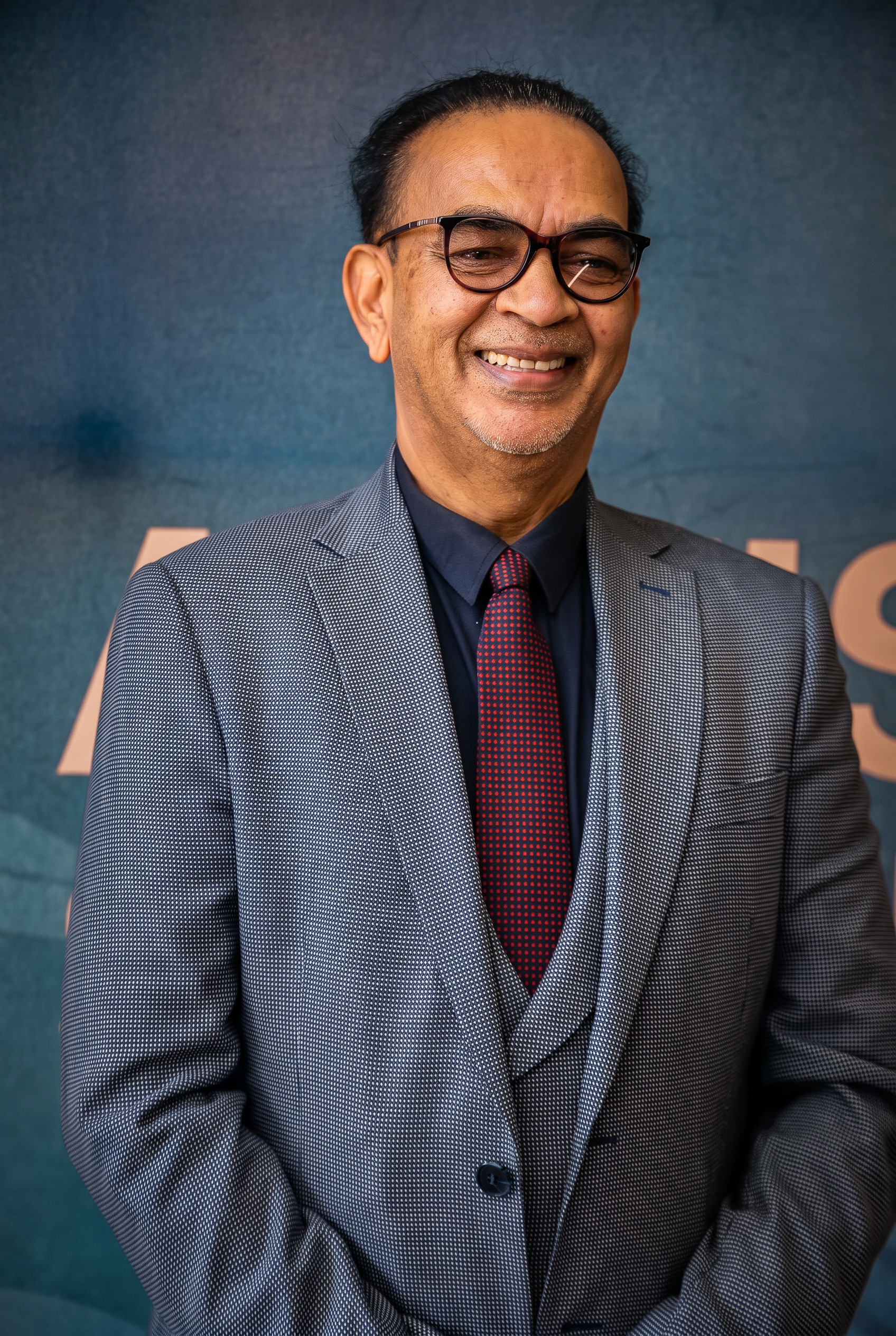 SANAA selection committee chairperson smiling in front of the awards backdrop